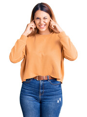 Poster - Beautiful young woman wearing casual clothes covering ears with fingers with annoyed expression for the noise of loud music. deaf concept.