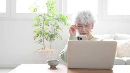 Wall Mural - smiling senior woman holding a smart phone (smartphone) video of a senior woman with difficulty seei