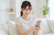 © siro46 - リビングでスマートフォンを使う若い女性