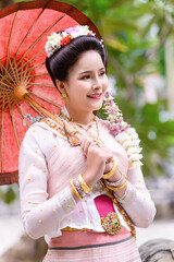 A young Thai woman dressed in traditional Northern Thailand culture costume visits a temple in Chiang Mai, Thailand.