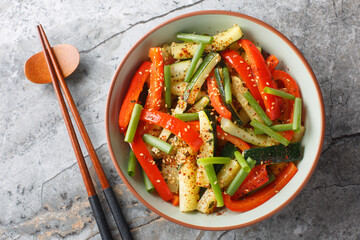 Wall Mural - Asian style fried vegetables zucchini, green onions and bell pepper close-up in a bowl on the table. Horizontal top view from above