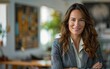 © imagineRbc - A confident businesswoman stands in a modern office space with arms crossed, smiling at the camera