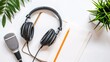 © mahamad - Technology, Sound Recording, and Podcast Concept: On a white background, headphones, a microphone, and a notebook with a pencil depict elements related to technology, sound recording, and podcasting.