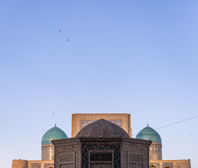 The building has a blue dome and is surrounded by a blue sky. There are birds flying in the sky above the building