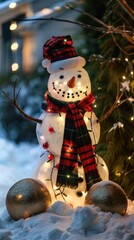 Poster - A snowman with a red and black plaid scarf stands in the snow with lights strung around its body. The snowman is illuminated by the warm glow of string lights, creating a festive atmosphere. The snowm