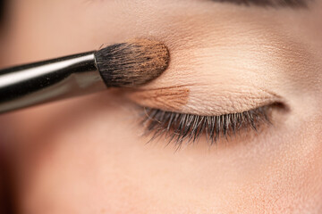 makeup artist using makeup brush for eyes and applying brown eyeshadow. make-up for young asian girl.