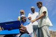 © ADDICTIVE STOCK - Multiethnic group of friends using tablet outdoors