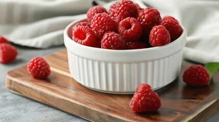Wall Mural - Ripe sweet raspberries in a white bowl on a wooden board