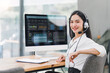 © kenchiro168 - Smiling operator wearing headset, using performance dashboard on desktop screen at office.