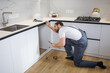 © Ivan - handyman worker in uniform fixing, installing furniture and equipment in the kitchen