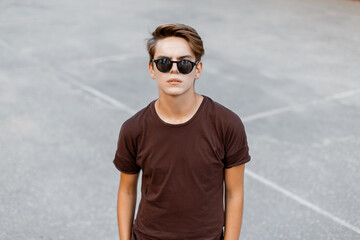 Wall Mural - Cool fashion young man with hairstyle with sunglasses in a T-shirt on the street