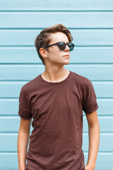 Wall Mural - Young handsome stylish man with hairstyle wearing fashionable sunglasses with t-shirt on blue vintage wooden background