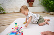 © Taras Grebinets - Cute baby playing with toys on a blanket outdoors