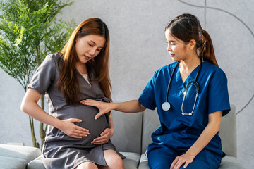 Wall Mural - Smiling asian pregnant woman visiting doctor in prenatal clinic. Beautiful pregnant woman listening doctor advise on sofa. Closeup obstetrician consulting pregnant woman in hospital office.