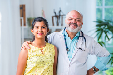 Wall Mural - Portrait of Happy Indian asian girl child patient with senior elderly old male doctor pointing