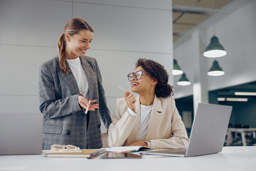 Smiling business woman work together to get the job done at the office and use laptop