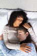 © Wavebreak Media - Two women lie on a bed, embracing and resting together in affection and comfort