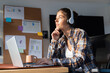 © Wavebreak Media - Wearing headphones and using laptop, young woman is working at home
