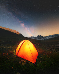 Wall Mural - Camping in the mountains. A broken tent under the glowing stars of the night sky of the Milky Way against the backdrop of snow-capped mountains. Natural landscape