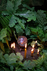 Sticker - Burning candles, quartz crystal ball, fern and oak leaves in forest, natural background. crystal ball for meditation, relaxation. Witchcraft. magic healing mineral. wiccan spiritual esoteric practice