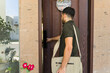 © AntonioDiaz - Man carrying a should bag and opening the front door of his house on a sunny day