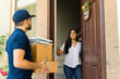 © AntonioDiaz - Happy woman receiving a home delivery from a delivery man holding cardboard boxes at the entrance of a house