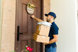 © AntonioDiaz - Latin delivery man holding cardboard boxes and knocking the door of a house to deliver a package