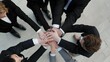 © Summit Art Creations - A group of business professionals in suits and formal attire join their hands together over a table during a meeting to show unity and teamwork. AIG535