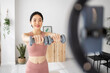 © Xavier Lorenzo - Young influencer asian woman recording fitness video tutorials for social media network at home.