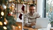 © Anastasiia - Man working on laptop at home decorated for Christmas with tree, stockings, and festive lights, enjoying the holiday season.
