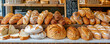 © Volodymyr - A bakery counter with an array of bread loaves, rolls, and baguettes, with a chalkboard menu in the background. Bright, warm lighting highlights the freshness.