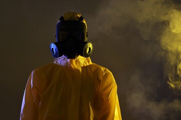 Wall Mural - Worker wearing gas mask in smoke on dark background. Space for text