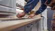 © Oulaphone - A worker install kitchen cabinets and counter of a beautifully designed kitchen.