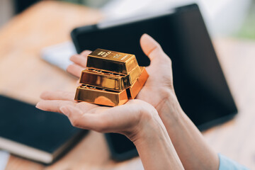 Portrait of a beautiful young businesswoman holding gold bar at office desk