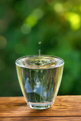 Wall Mural - glass of water with splash and drop on wooden table