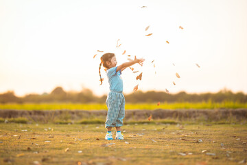 baby girl with happy time on freedom in emotional in outdoor by play throw leaves on grass floor in blue dress