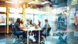 © Alex - A blurred view through a glass wall into a bustling modern office, showcasing a team collaborating at a table with a whiteboard filled with handwritten notes