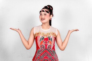 A young woman wearing a batik shirt is excited presenting and showing copy space, isolated on a white background