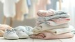 © สมชัย ้พาลแก้ว - Stack of baby clothes with baby shoes. Cotton clothes and muslin swaddle blanket in pastel colors. Clean freshly laundered, neatly folded kids clothes