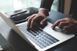 © tippapatt - Closeup of businessman hand typing on laptop computer at office. Business man working on computer device, searching the information, surfing the internet on table at workplace