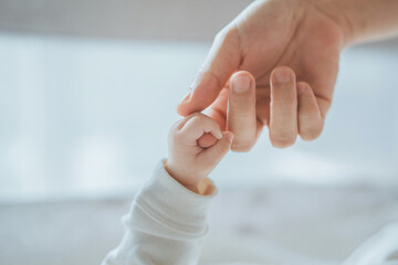 close-up little hand of child baby holding hand of mother, a newborn holds on to mom's, dad's finger