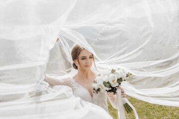 Wall Mural - A bride is standing in front of a white veil, holding a bouquet of flowers. The scene is set in a field, with the bride's dress billowing in the wind. Scene is one of celebration and joy