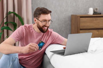 Canvas Print - Online banking. Happy young man with credit card and laptop paying purchase at home