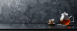© AI_images - A minimalist tea background with a modern glass teapot, a single cup, and a tea infuser on a sleek black countertop