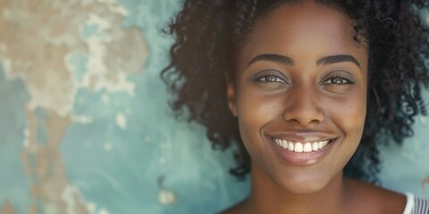 A woman with curly hair smiling directly at the camera, a simple and cheerful expression