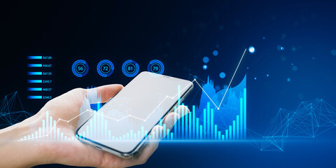 Wall Mural - Hand holding a smartphone with holographic graphs floating above it, against a blue technology-themed background, representing a concept of business analytics