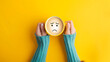 © alexandre - A woman hands holding a cup of coffee with a sad face emoji on a yellow background with copu space for text bad emotions morning mood.