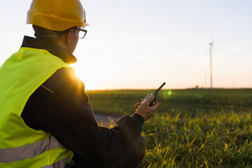 Poster - Worker sits on the grass and looks at wind turbines