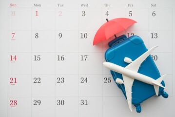 Airplane, suitcase and umbrella on white calendar background. Travel holiday or annual leave travel period for relaxation concept. Period of paid time off (PTO) granted to employees by their employer.