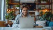 © visoot - A man smiling using a laptop on a video call, with headphones, in office, in the morning. Generative AI.